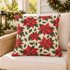 Red Christmas poinsettia outdoor pillow on a rattan porch chair with Christmas garland and warm lights