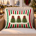 Red stripe Christmas tree outdoor lumbar pillow on a rattan chair on a snowy Christmas porch