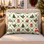 Cream Christmas village outdoor lumbar pillow on a rattan chair on a snowy Christmas porch