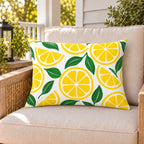 Yellow lemon citrus outdoor lumbar pillow on a rattan chair on a sunny summer porch