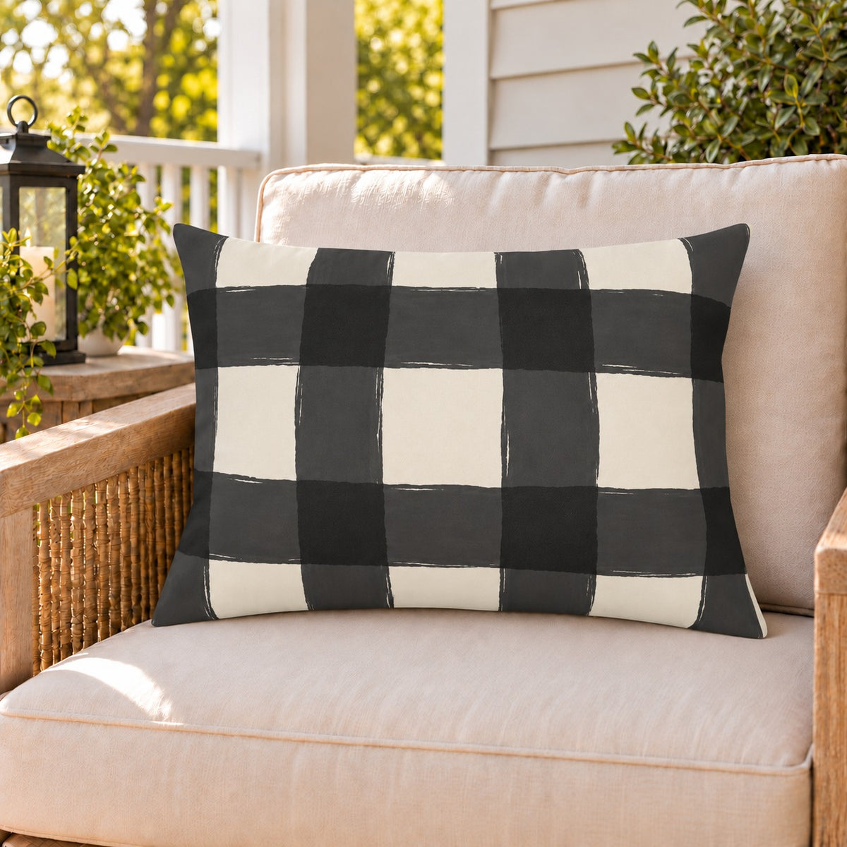 Black and white gingham check outdoor lumbar pillow on a rattan chair on a sunny summer porch