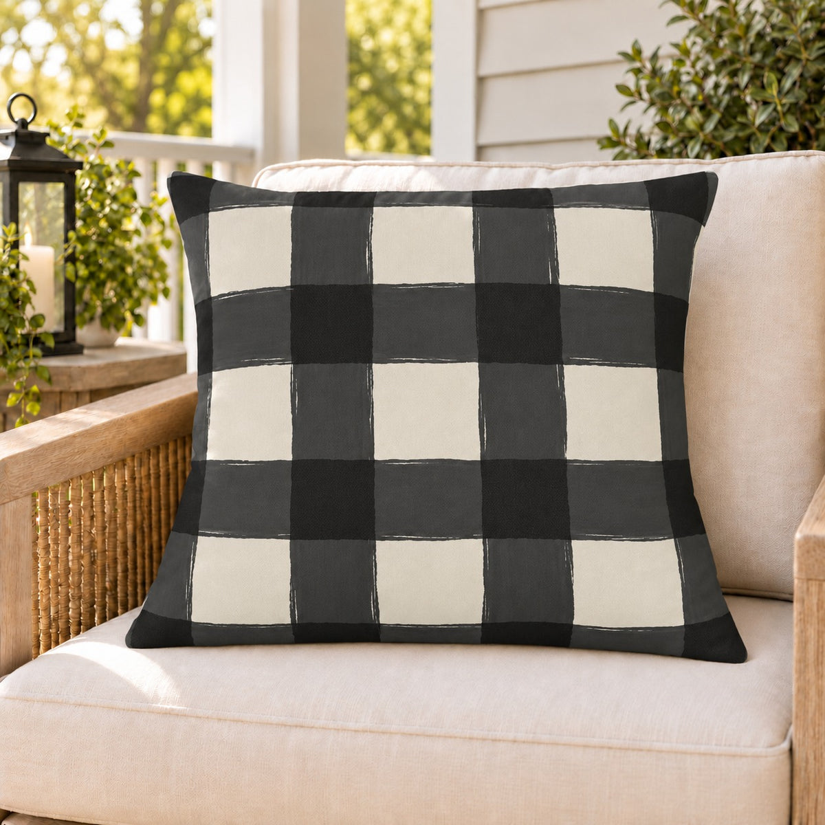Black and white gingham check outdoor pillow on a rattan chair on a sunny summer porch