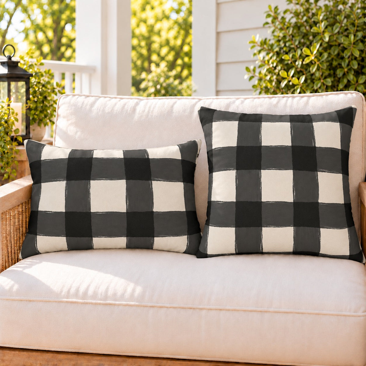Black and white gingham check outdoor pillow and outdoor lumbar pillow styled together as a set on a porch loveseat