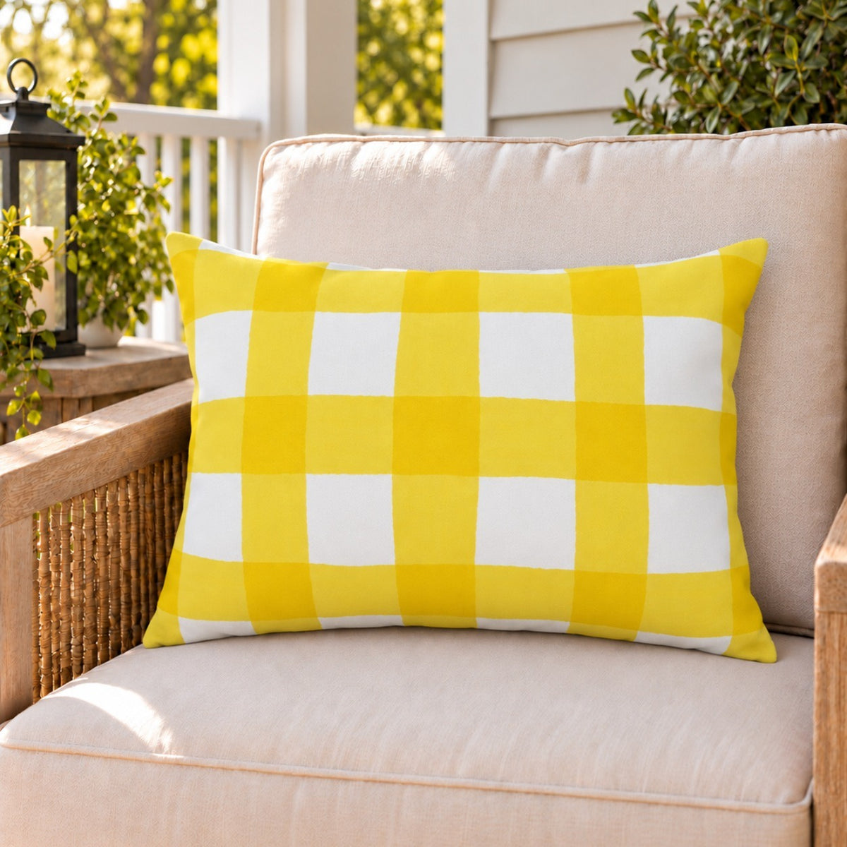Yellow gingham check outdoor lumbar pillow on a rattan chair on a sunny summer porch