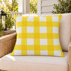 Yellow gingham check outdoor pillow on a rattan chair on a sunny summer porch