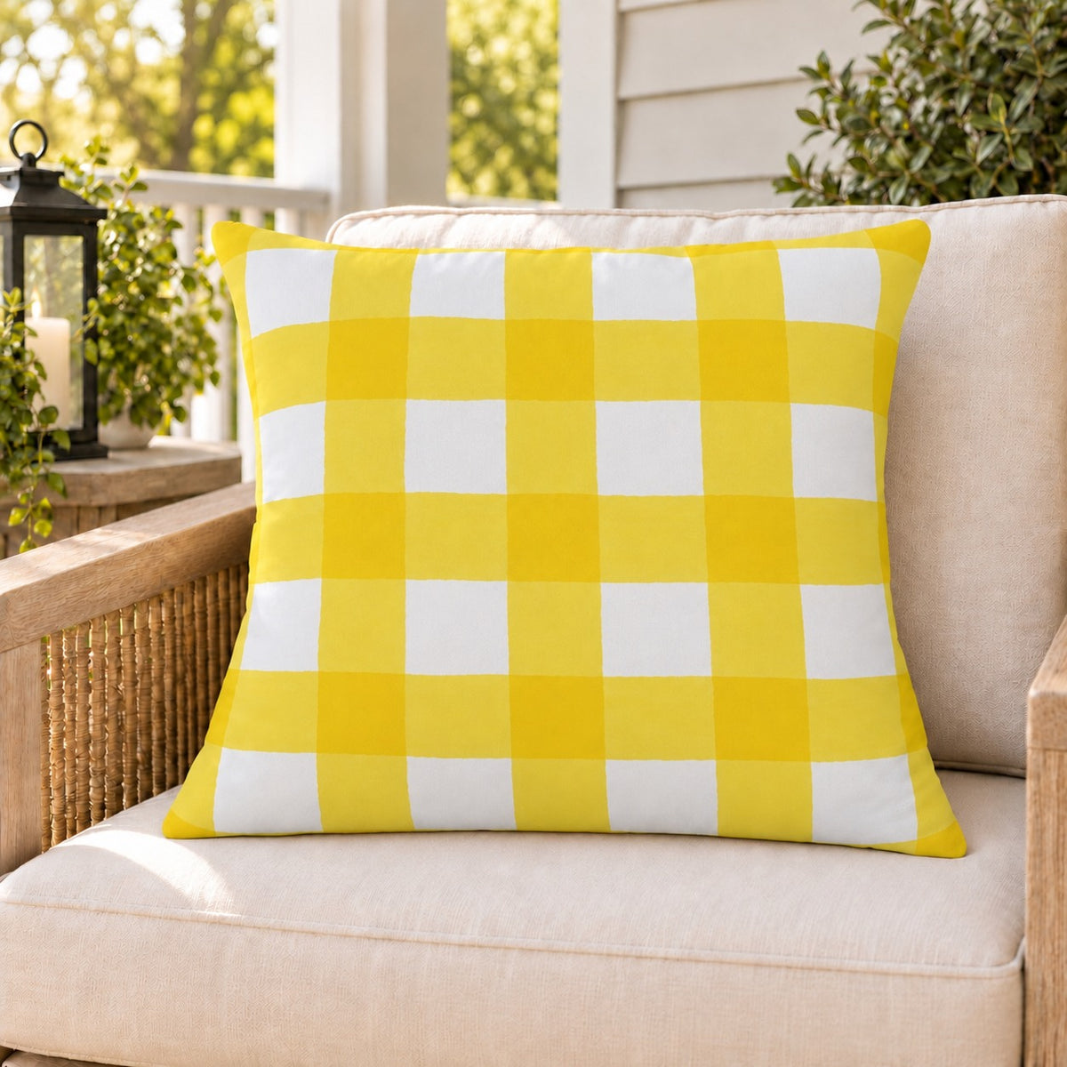 Yellow gingham check outdoor pillow on a rattan chair on a sunny summer porch
