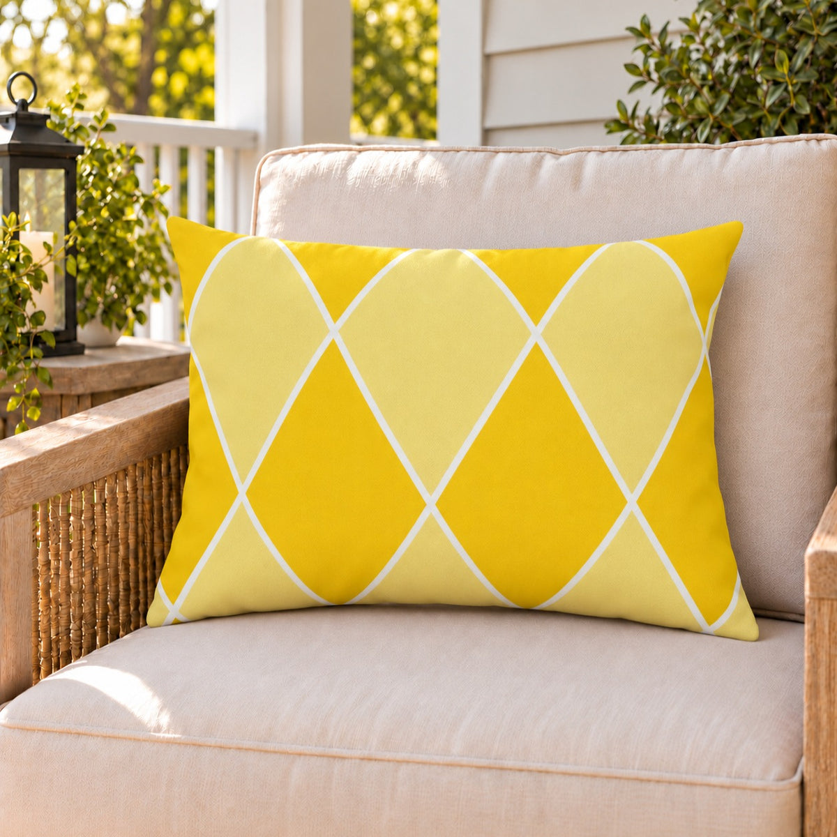 Yellow harlequin diamond outdoor lumbar pillow on a rattan chair on a sunny summer porch