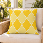 Yellow harlequin diamond outdoor pillow on a rattan chair on a sunny summer porch