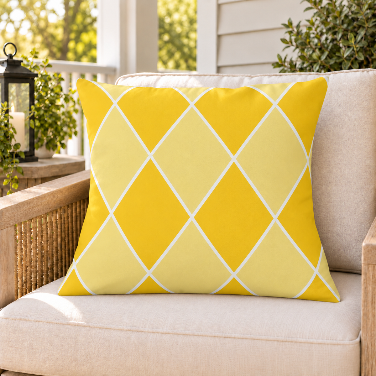 Yellow harlequin diamond outdoor pillow on a rattan chair on a sunny summer porch