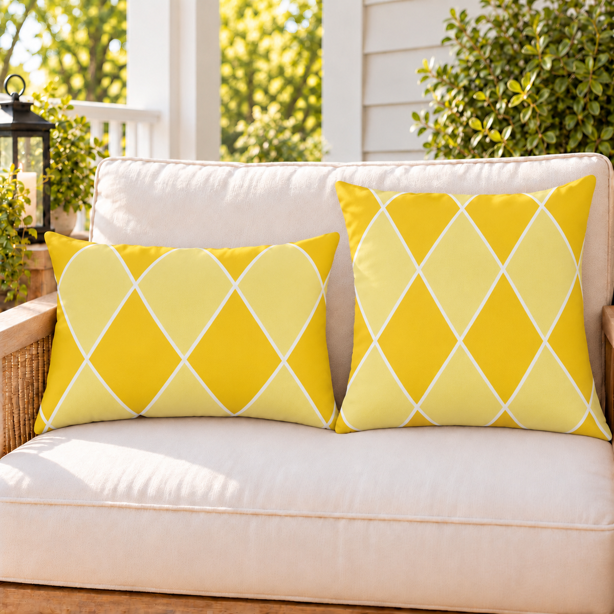Yellow harlequin diamond outdoor pillow and outdoor lumbar pillow styled together as a set on a porch loveseat