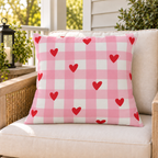 Heart Gingham Pink outdoor pillow on a rattan chair on a sunny summer porch