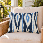 Navy and white ikat stripe outdoor lumbar pillow on a rattan chair on a sunny summer porch