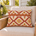 Moroccan Kilim Rust outdoor lumbar pillow on a rattan chair on a sunny summer porch