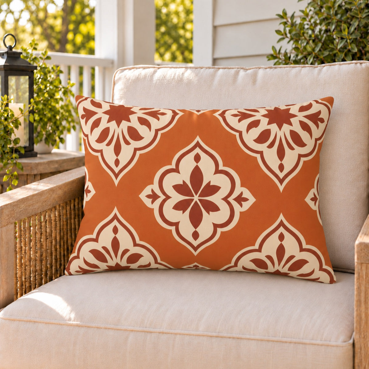 Moroccan Medallion Burnt Orange outdoor lumbar pillow on a rattan chair on a sunny summer porch