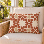 Moroccan Zellige Star Terracotta outdoor lumbar pillow on a rattan chair on a sunny summer porch