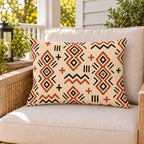 Terracotta mudcloth boho outdoor lumbar pillow on a rattan chair on a sunny summer porch