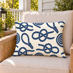 Nautical rope knot outdoor lumbar pillow on a rattan chair on a sunny summer porch