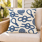 Nautical rope knot outdoor pillow on a rattan chair on a sunny summer porch