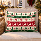 Red Nordic reindeer outdoor lumbar pillow on a rattan chair on a snowy Christmas porch