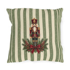 Sage green Christmas nutcracker outdoor pillow with a nutcracker, pine and a burgundy ribbon on sage and cream stripes