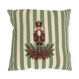 Sage green Christmas nutcracker outdoor pillow with a nutcracker, pine and a burgundy ribbon on sage and cream stripes