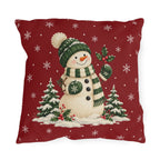 Christmas snowman outdoor pillow with a green bobble hat and striped scarf on red with white snowflakes