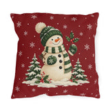 Christmas snowman outdoor pillow with a green bobble hat and striped scarf on red with white snowflakes