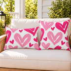 Painted Heart Hot Pink outdoor pillow and outdoor lumbar pillow styled together as a set on a porch loveseat