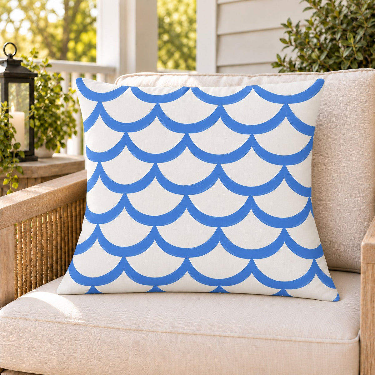 Blue painted scallop outdoor pillow on a rattan chair on a sunny summer porch