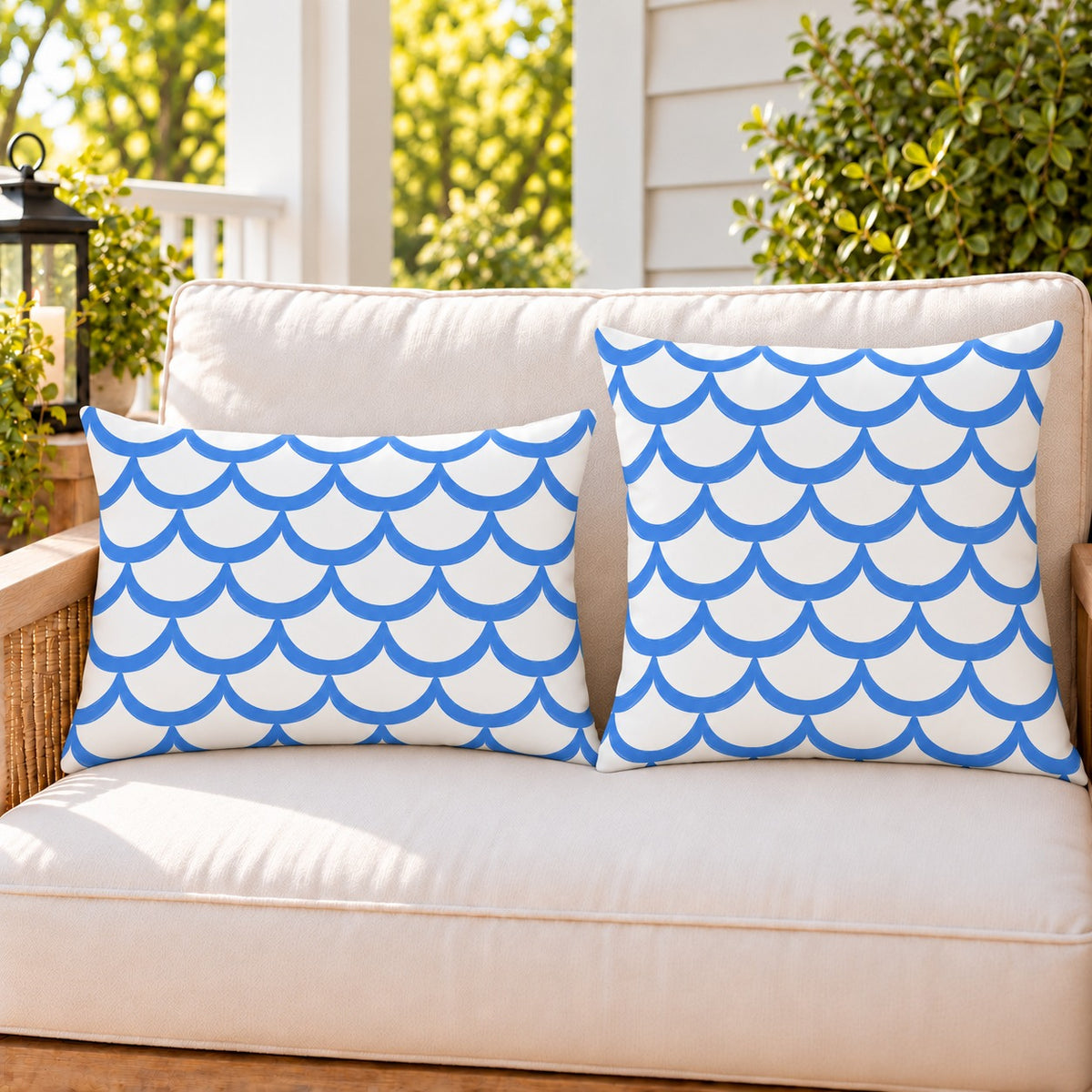 Blue painted scallop outdoor pillow and outdoor lumbar pillow styled together as a set on a porch loveseat