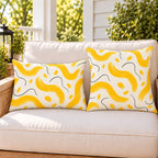 Yellow painted wave outdoor pillow and outdoor lumbar pillow styled together as a set on a porch loveseat