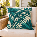 Teal palm frond outdoor pillow on a rattan chair on a sunny summer porch