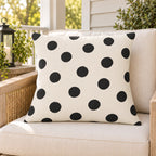 Black and white polka dot outdoor pillow on a rattan chair on a sunny summer porch