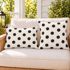 Black and white polka dot outdoor pillow and outdoor lumbar pillow styled together as a set on a porch loveseat