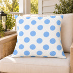 Light blue polka dot outdoor pillow on a rattan chair on a sunny summer porch