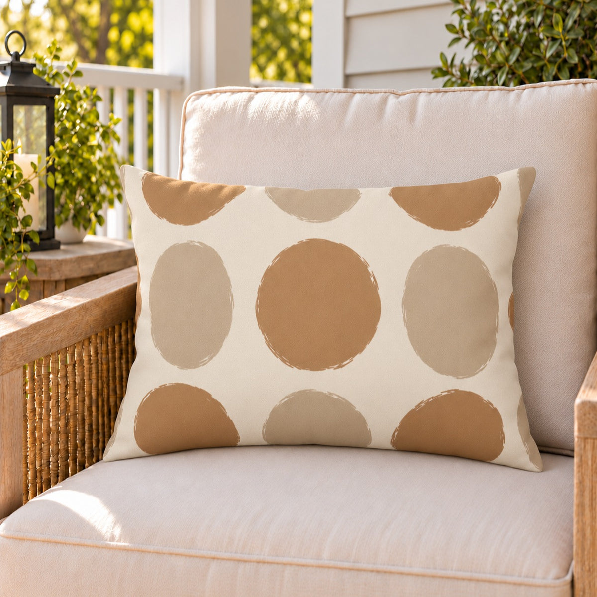 Sand polka dot outdoor lumbar pillow on a rattan chair on a sunny summer porch