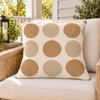 Sand polka dot outdoor pillow on a rattan chair on a sunny summer porch