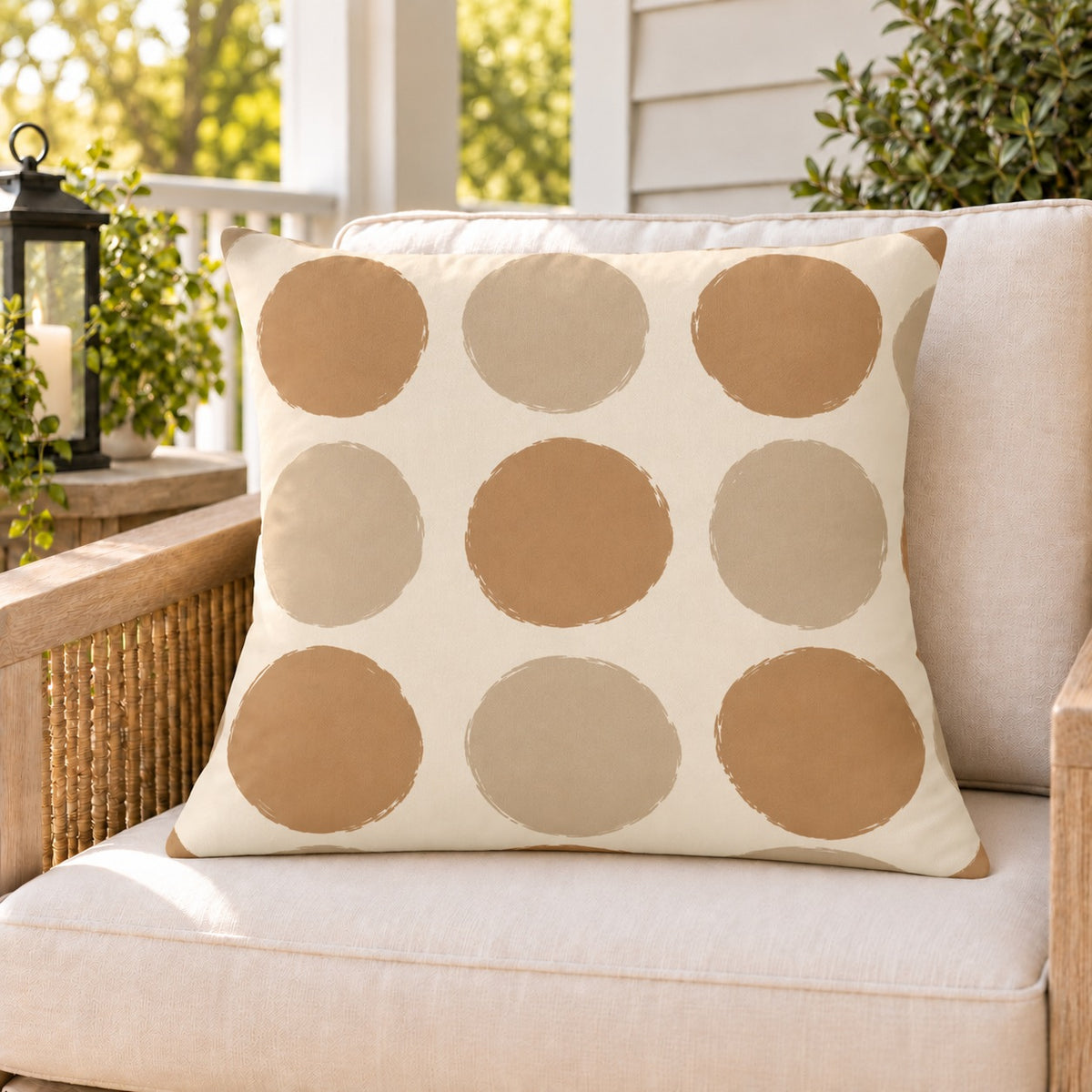 Sand polka dot outdoor pillow on a rattan chair on a sunny summer porch