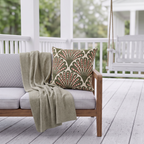 Green and red dotted fan outdoor pillow styled on patio furniture