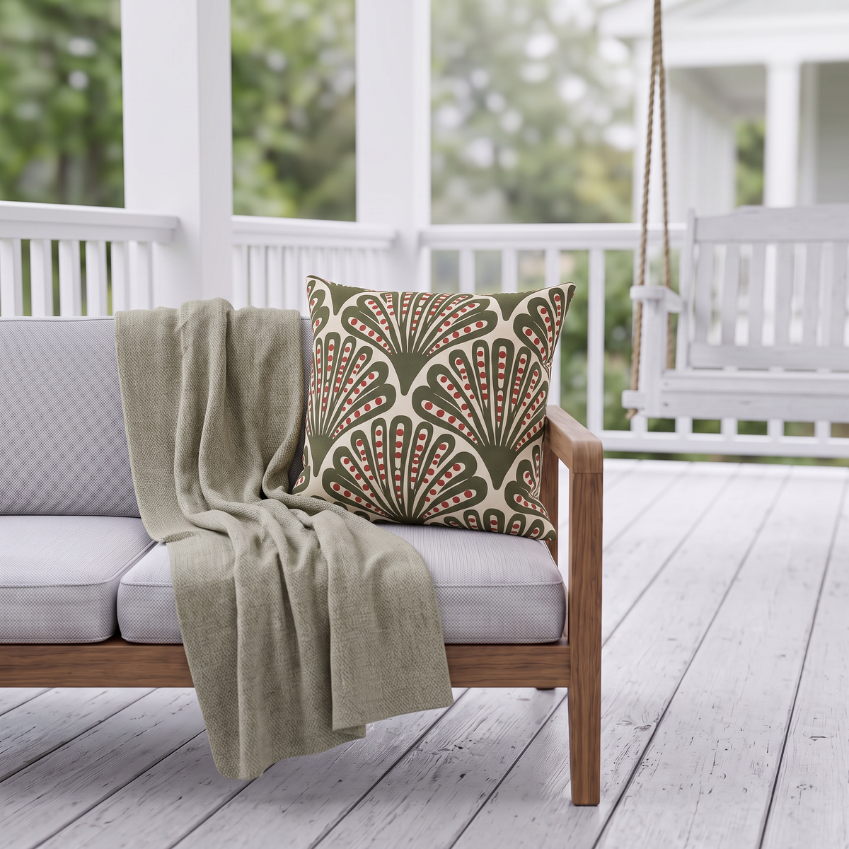 Green and red dotted fan outdoor pillow styled on patio furniture