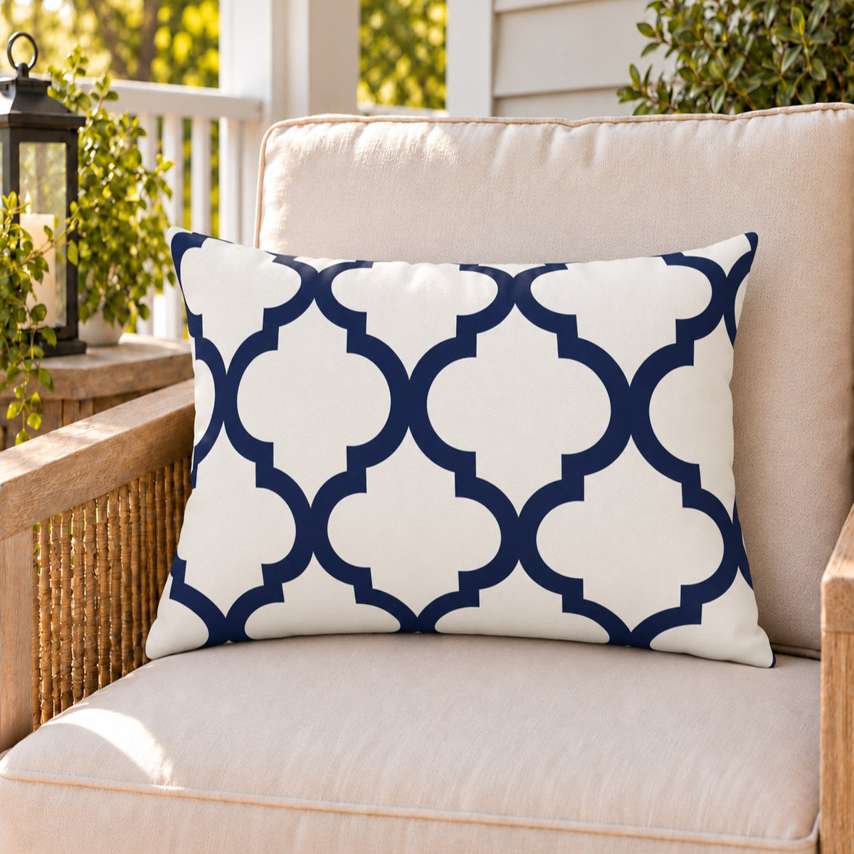 Navy quatrefoil outdoor lumbar pillow on a rattan chair on a sunny summer porch