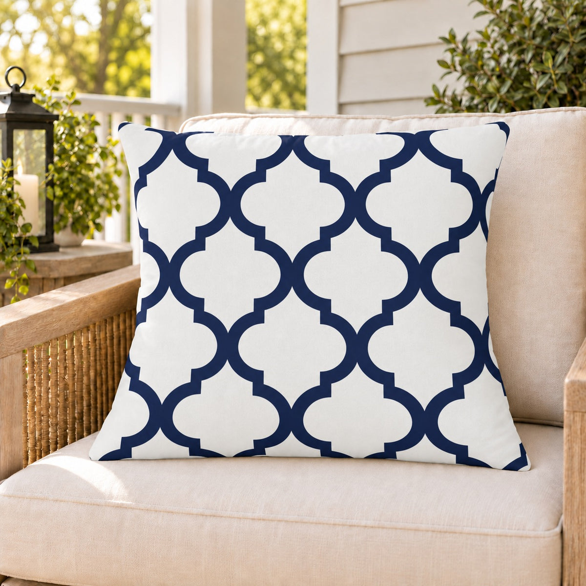 Navy quatrefoil outdoor pillow on a rattan chair on a sunny summer porch