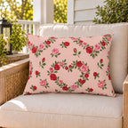 Rose Heart Blush outdoor lumbar pillow on a rattan chair on a sunny summer porch