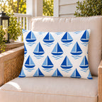 Blue sailboat outdoor lumbar pillow on a rattan chair on a sunny summer porch