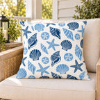 Blue seashell coastal outdoor pillow on a rattan chair on a sunny summer porch