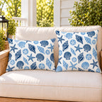 Blue seashell coastal outdoor pillow and outdoor lumbar pillow styled together as a set on a porch loveseat