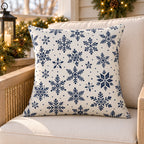 Navy snowflake outdoor pillow on a rattan porch chair with winter garland and warm lights