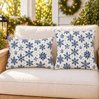 Navy snowflake outdoor pillow and outdoor lumbar pillow styled together as a set on a porch loveseat for winter