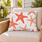 Coral starfish outdoor lumbar pillow on a rattan chair on a sunny summer porch