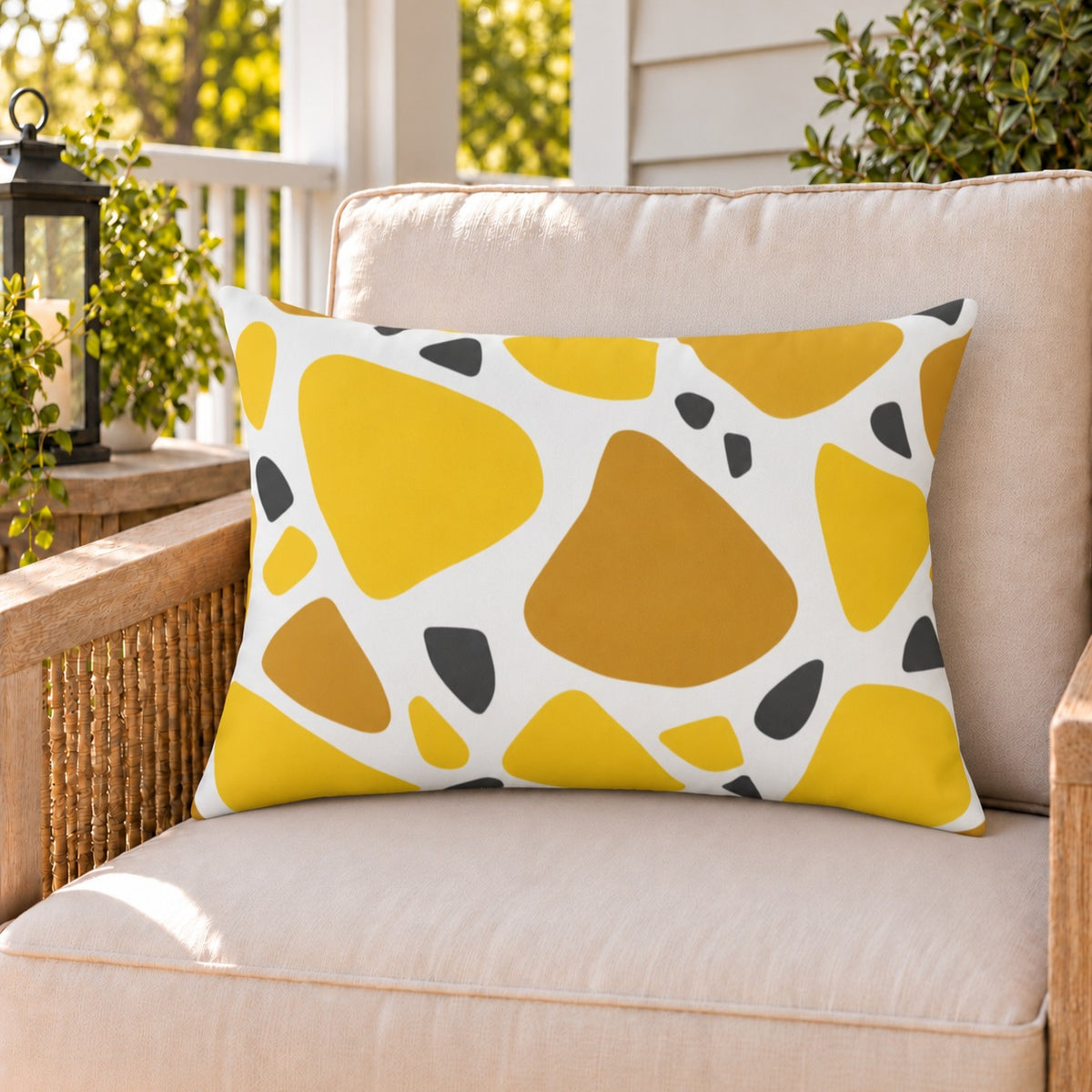 Yellow terrazzo outdoor lumbar pillow on a rattan chair on a sunny summer porch